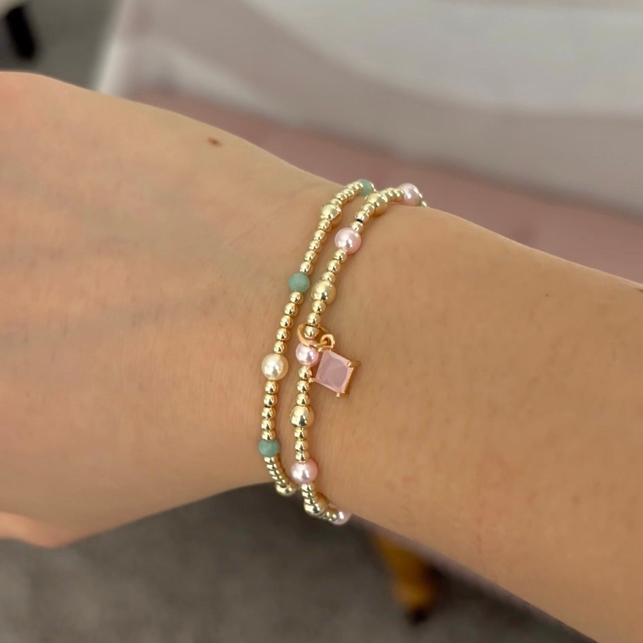 Gold beaded bracelet on a wrist with a blurred background