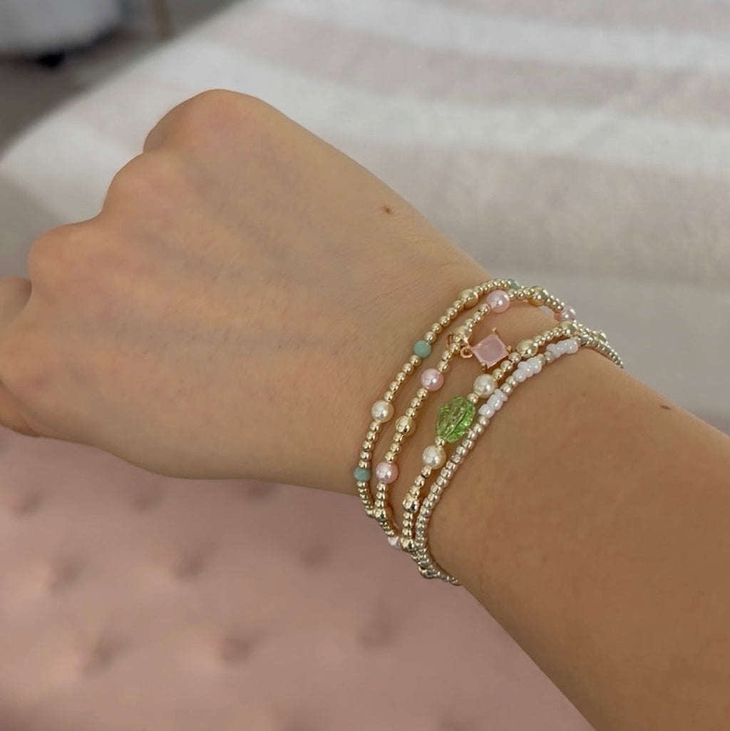 Wrist with multiple beaded bracelets on a neutral background
