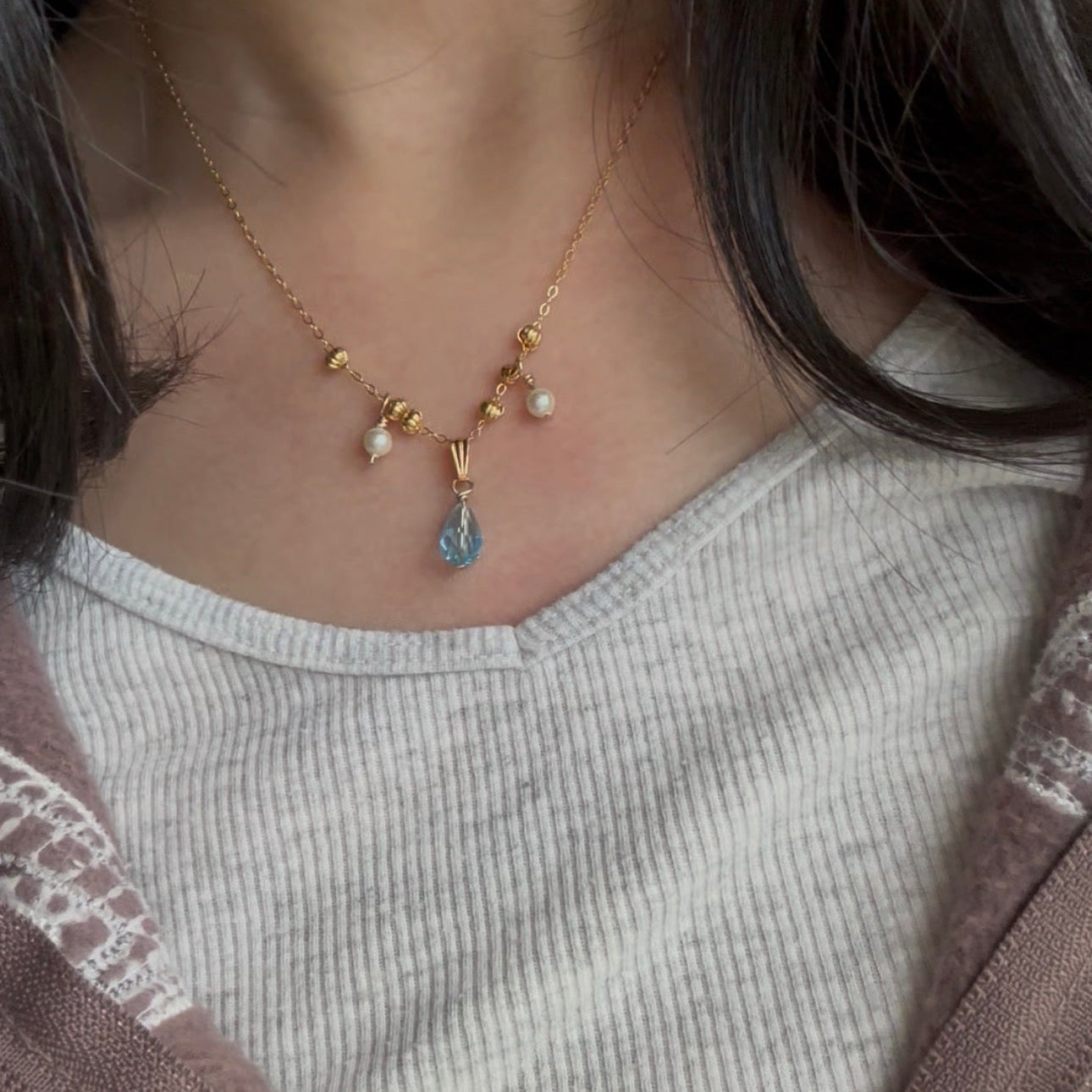 Necklace with a blue pendant worn by a person