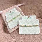 Two gold bracelets on display cards with 'tiny lilee' branding on a display card.
