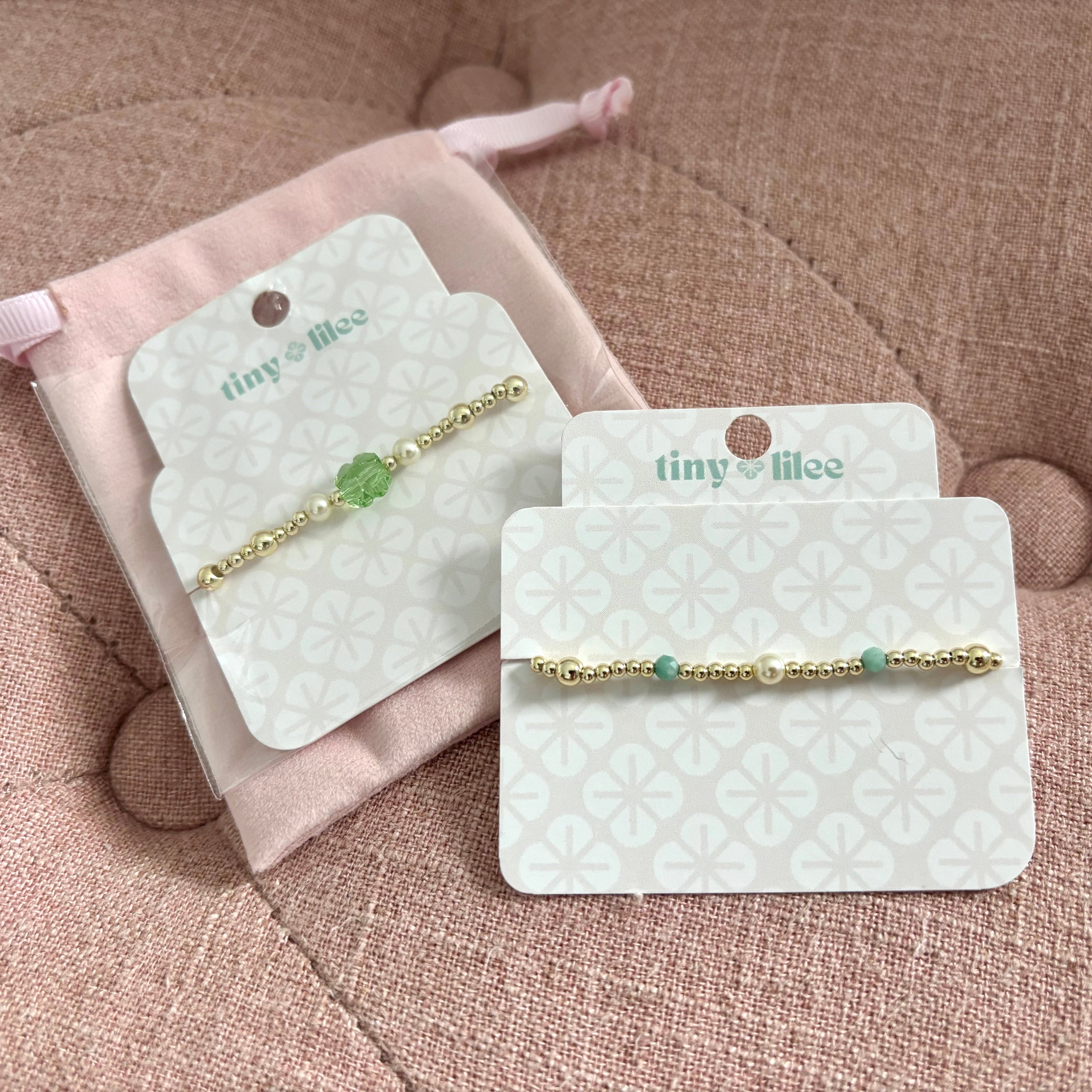 Two gold bracelets on display cards with 'tiny lilee' branding on a display card.