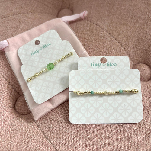 Two gold bracelets on display cards with 'tiny lilee' branding on a display card.