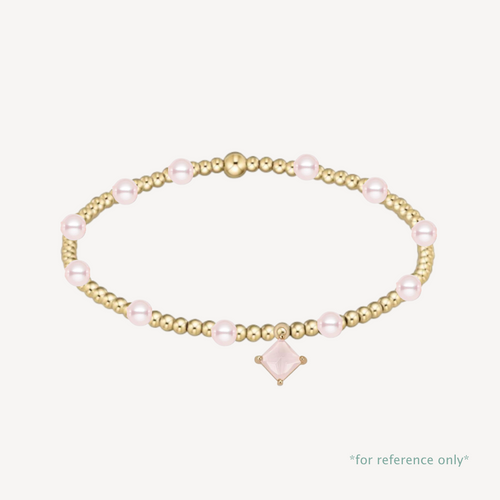 Gold and pink pearl bracelet on a white background with pink rhombus crystal charm