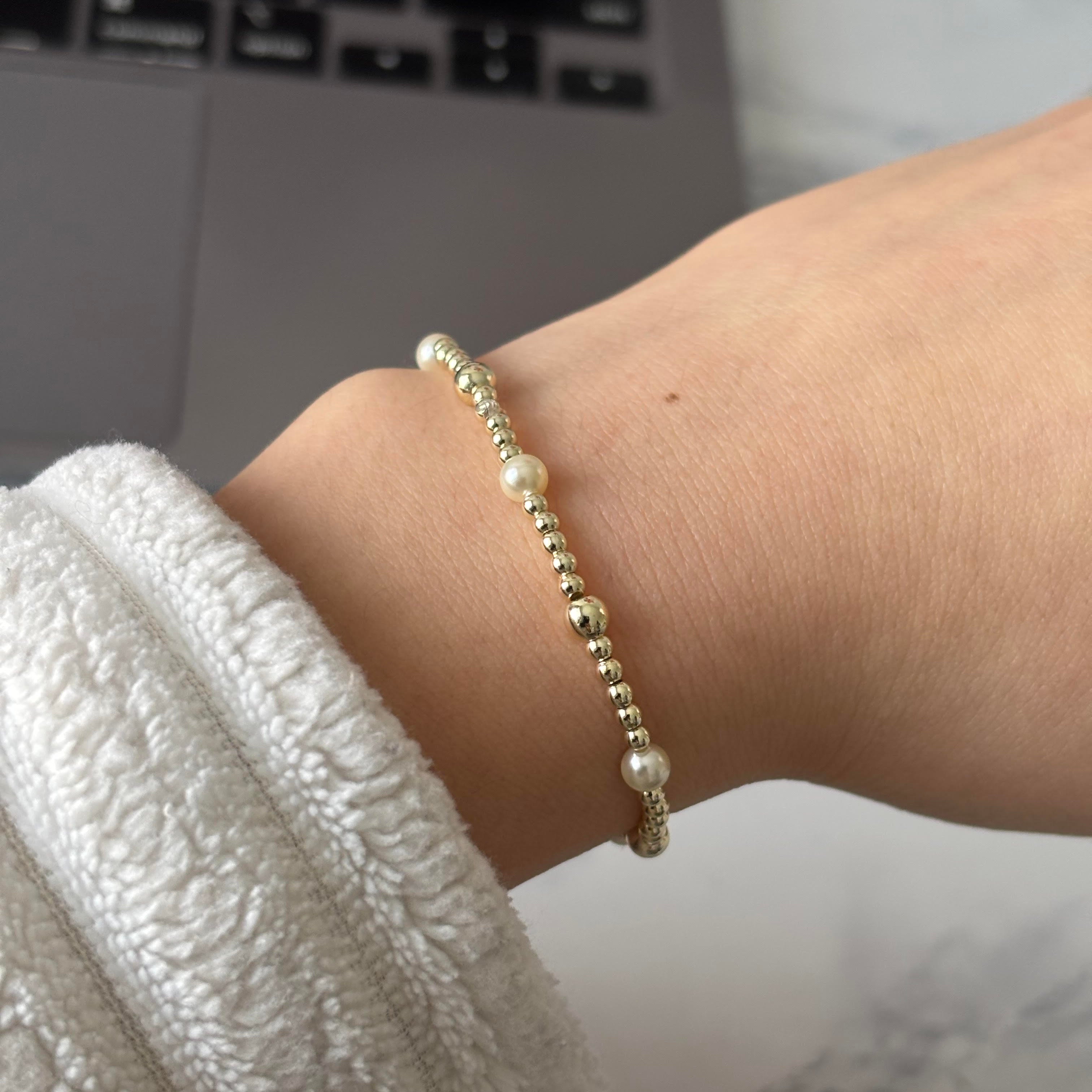 Gold beaded bracelet on a wrist with a blurred background