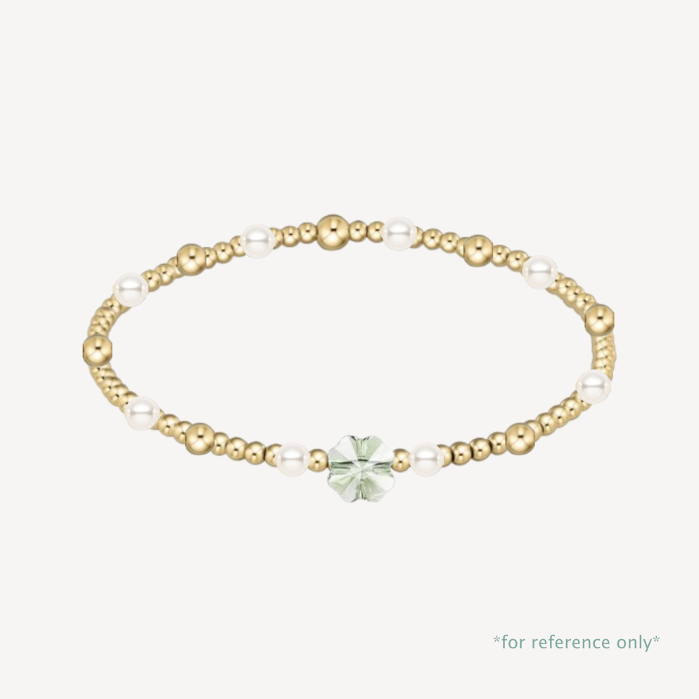 Gold and pearl bracelet with a green gemstone on a white background