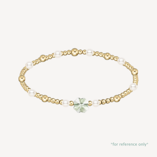 Gold and pearl bracelet with a green gemstone on a white background