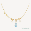 Gold necklace with a blue teardrop pendant and pearl accents on a white background