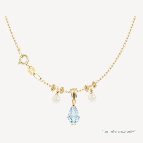 Gold necklace with a blue teardrop pendant and pearl accents on a white background