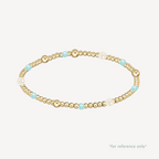Gold beaded bracelet with pearls and turquoise beads on a white background